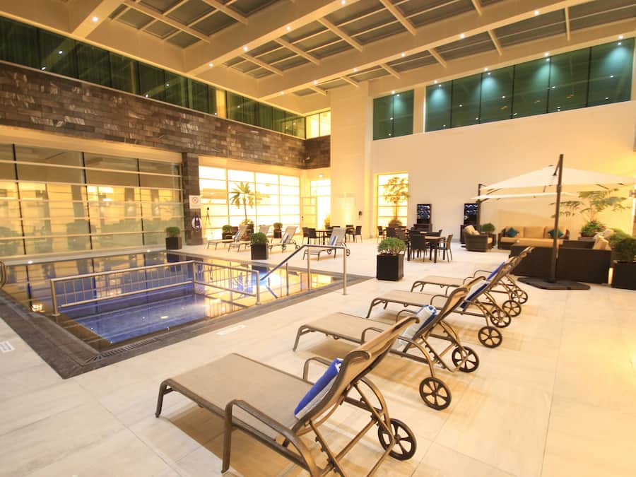 Amplio espacio interior con piscina, tumbonas y zona de estar con mesas y sillas.