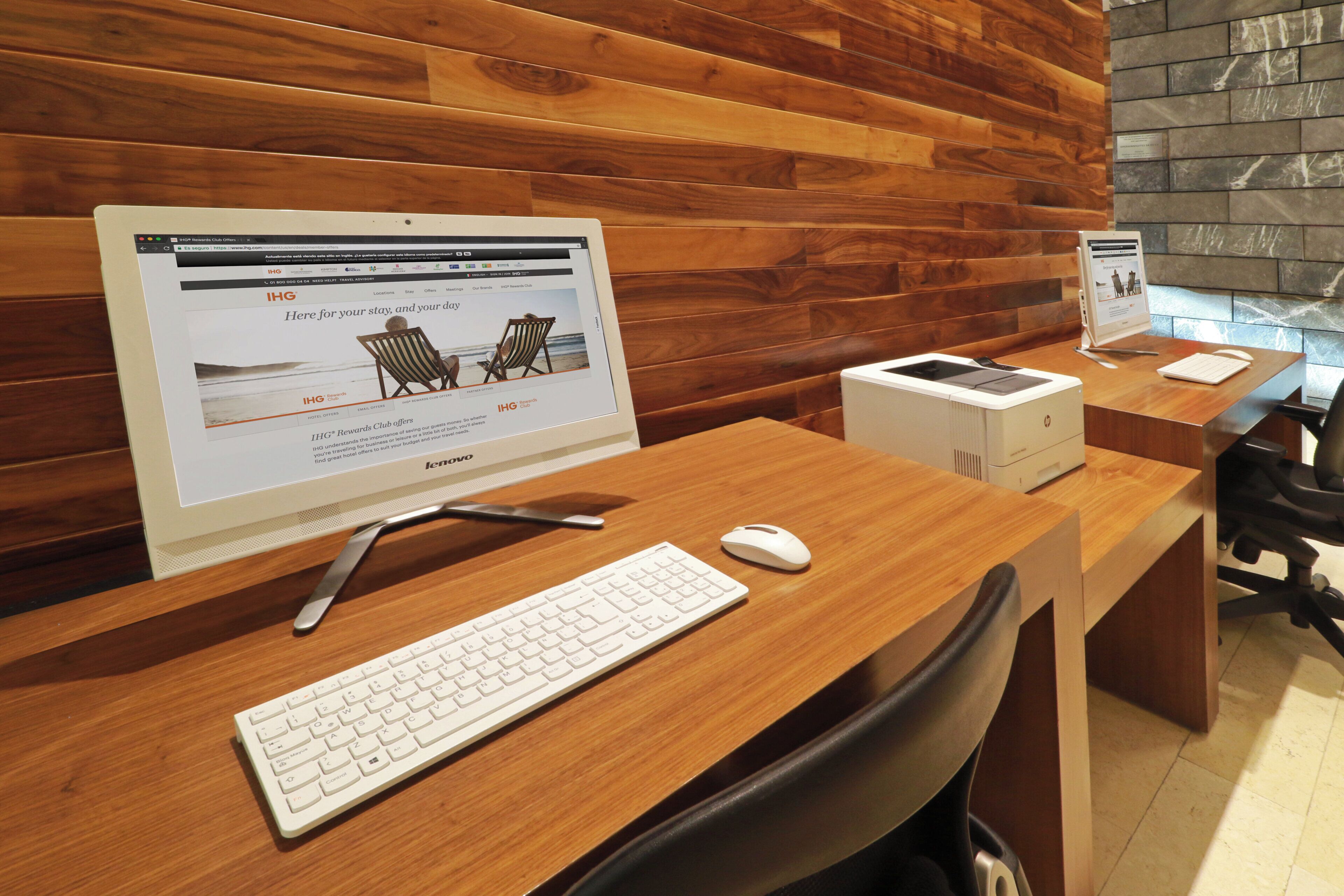 A hotel reception desk with a desktop computer, a keyboard, a mouse, and a printer.