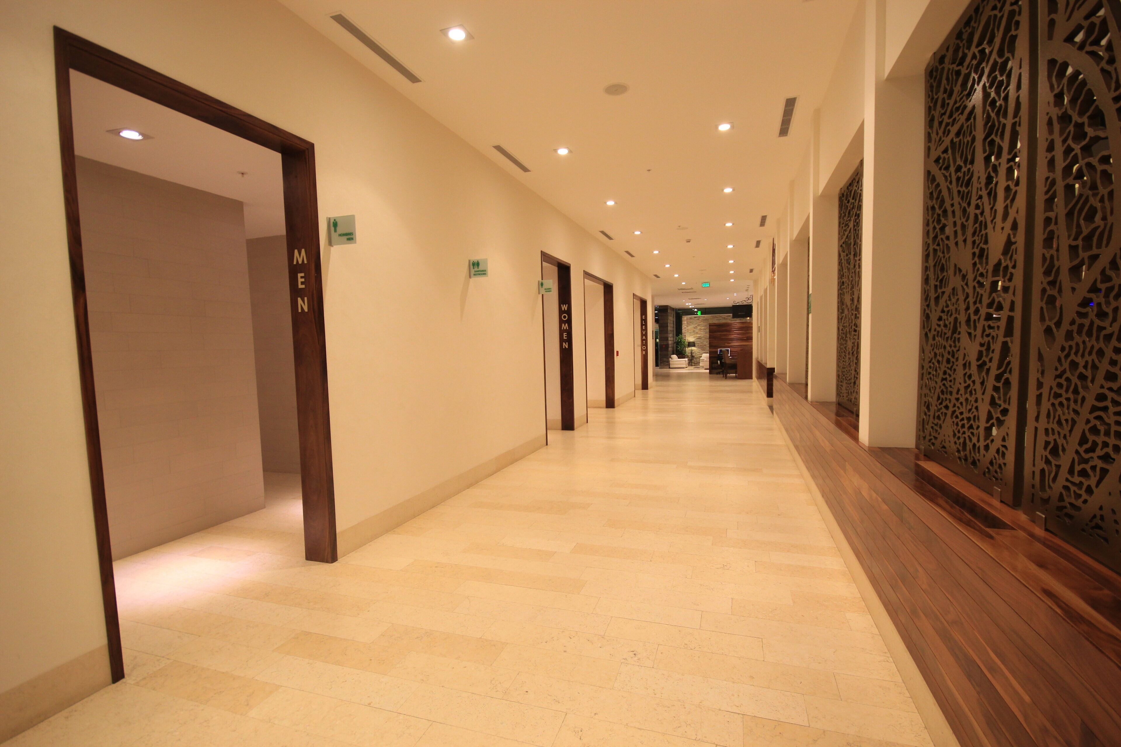 A hotel corridor with doors labeled 'MEN' and 'WOMEN' leading to rooms.