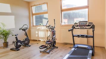 Uma academia com esteira, elíptico e bicicleta ergométrica.