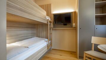 A bunk bed room with a TV and a chair.