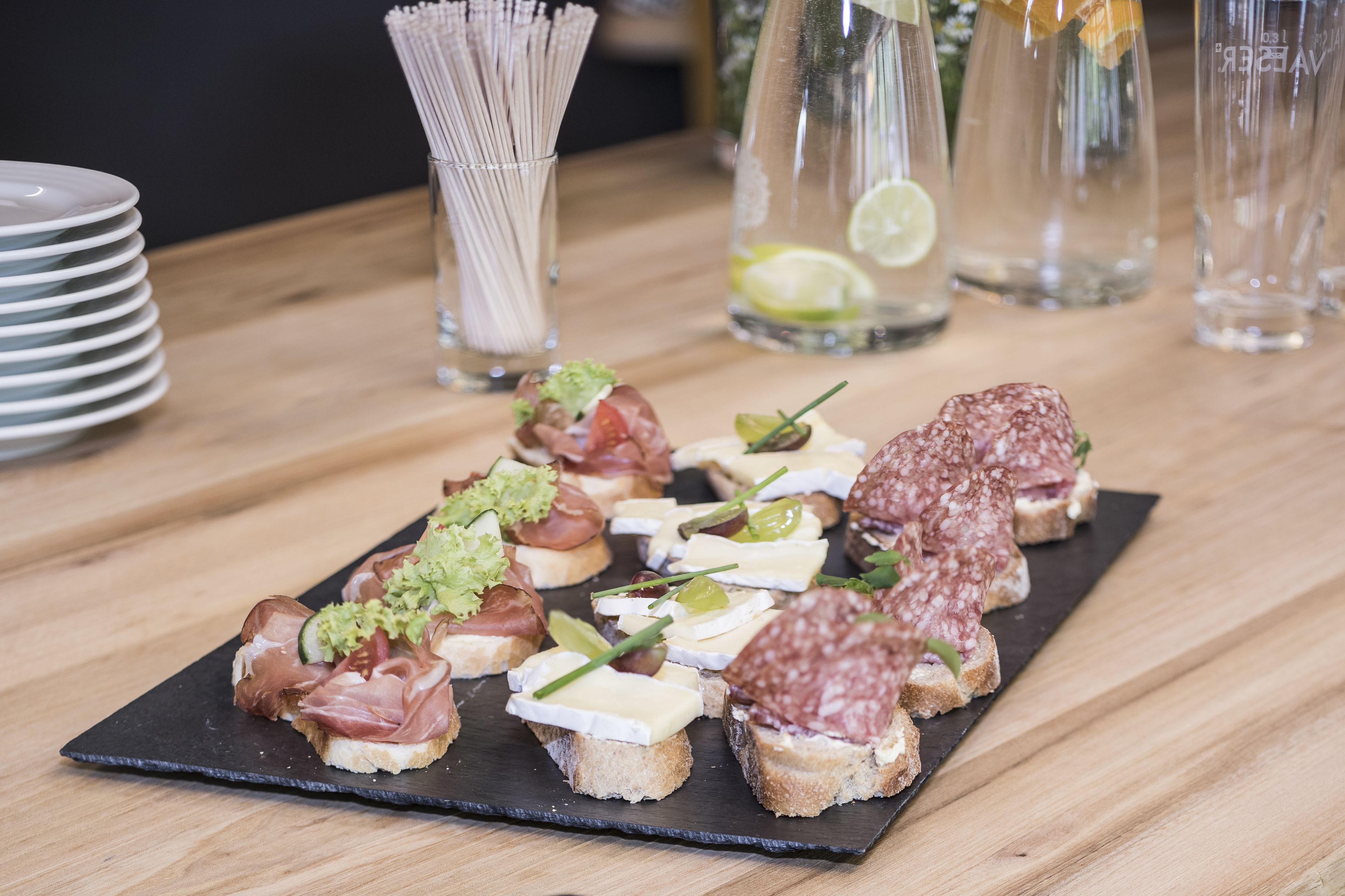 A variety of appetizers on a black slate board, including items with cheese, meats, and vegetables.