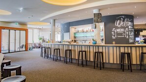 A modern bar area with a curved counter, stools, and a welcome sign. - JUFA Hotel Malbun (Triesenberg)