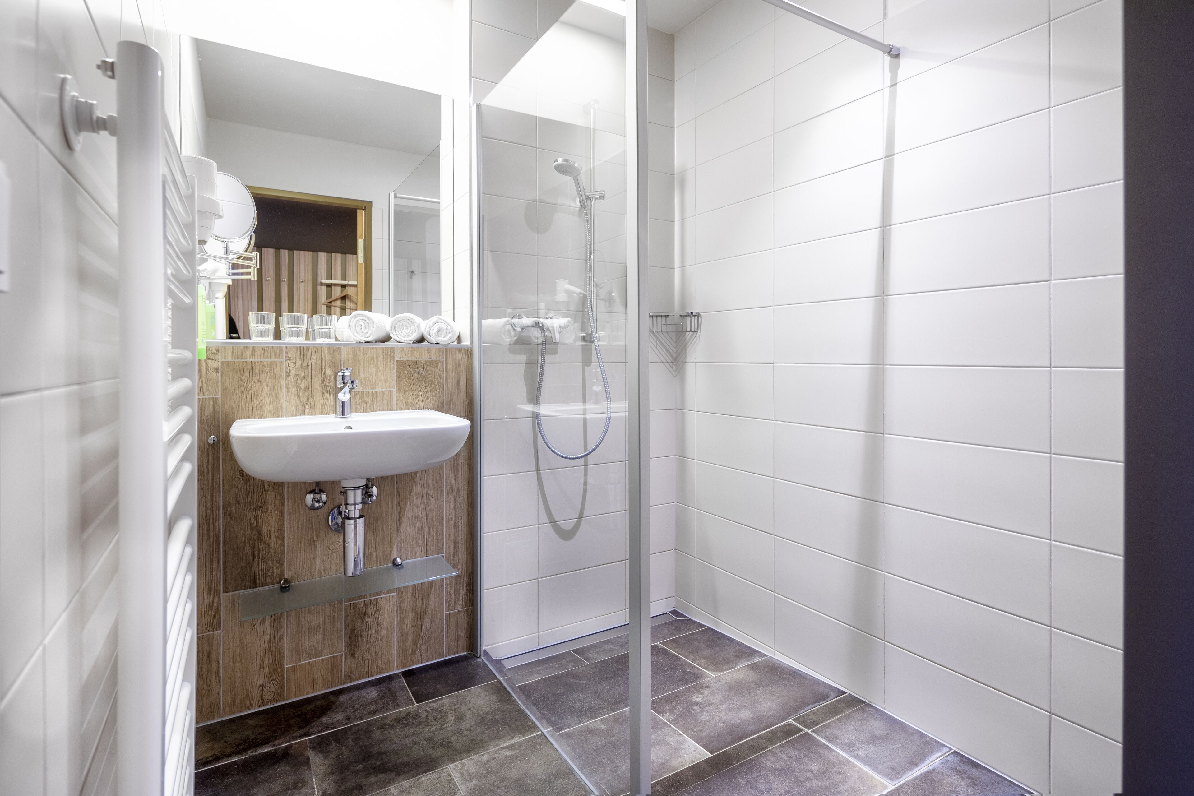 A modern bathroom with a glass-enclosed shower, a white sink, and a wooden vanity.