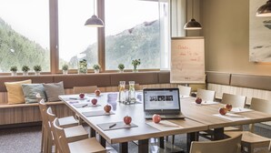 A conference room with a long table, chairs, a laptop, apples, and a whiteboard with writing. - JUFA Hotel Malbun (Triesenberg)