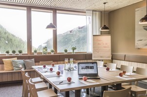 Un salón de conferencias con una larga mesa, sillas, una computadora portátil, manzanas y una pizarra con escritura.