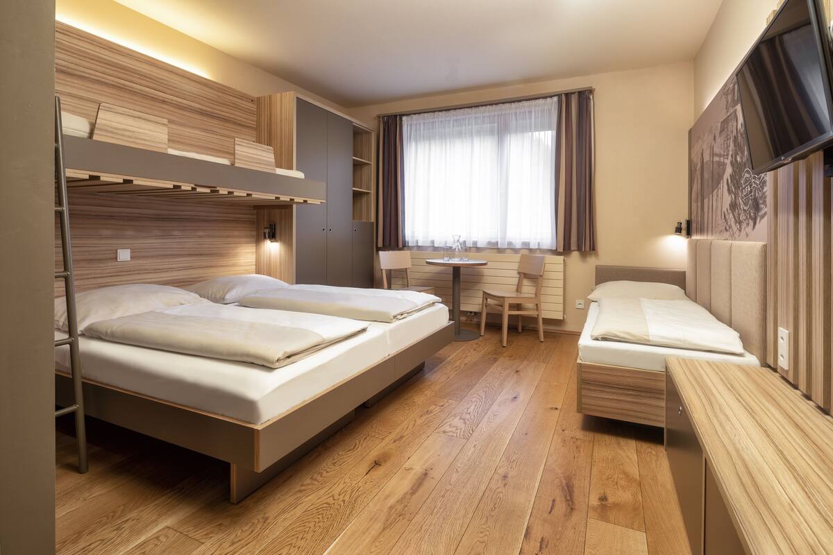 Une chambre d’hôtel de taille réduite, équipée de deux lits, d’une petite table et d’un téléviseur.