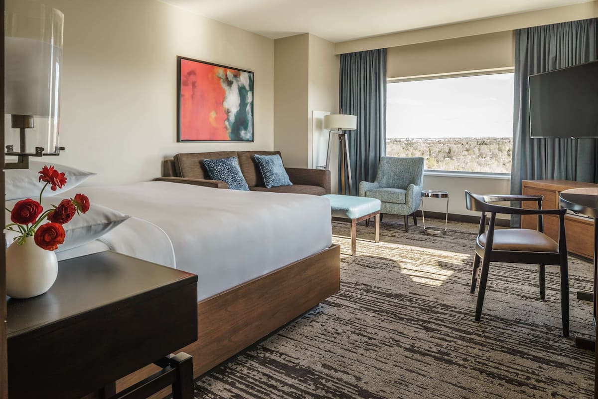 Une chambre d’hôtel avec un grand lit, un bureau, une chaise, un canapé et une télévision.
