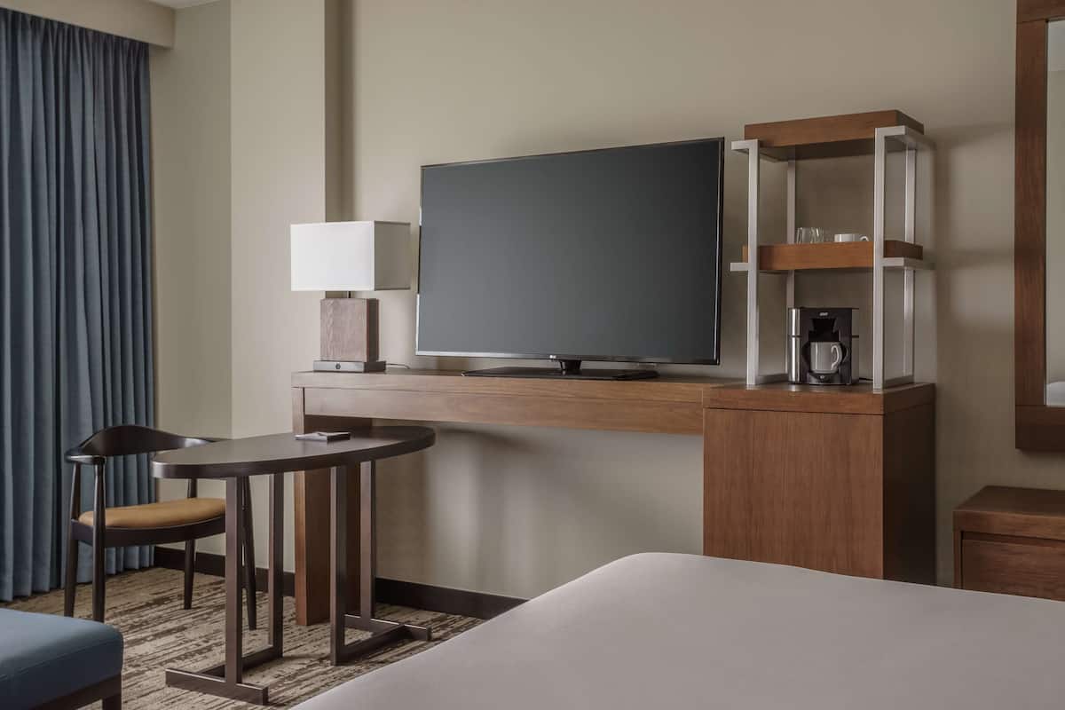 Une chambre d’hôtel équipée d’un lit, d’un bureau avec une télévision, d’une machine à café et d’une lampe.