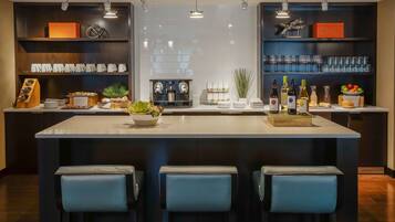 Una cocina moderna con una isla central, asientos tipo barra y diversos electrodomésticos y estanterías.