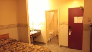 Una habitación de hotel con cama, baño y puerta.