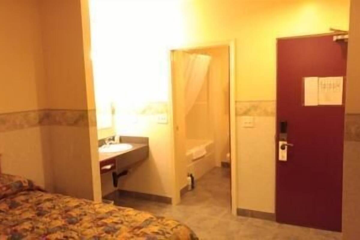 A hotel room with a bed, a bathroom, and a door.