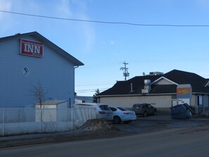 A building with a sign for Crossfield Country Inn, a fenced parking area, and a McDonald's sign.