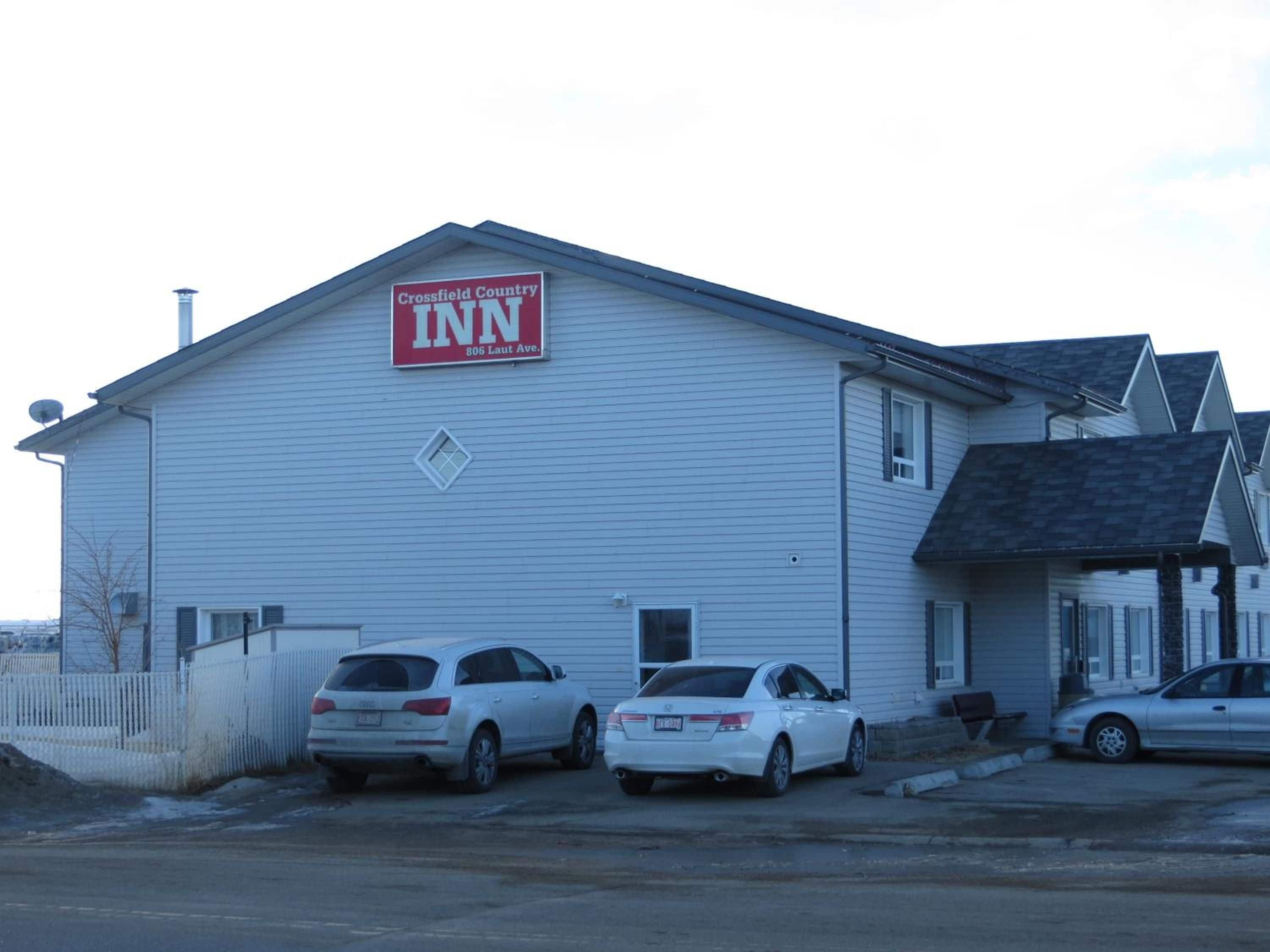 Un edificio con un cartel para Crossfield Country Inn, que presenta una estructura sencilla de un piso con techo a dos aguas y un pequeño porche.