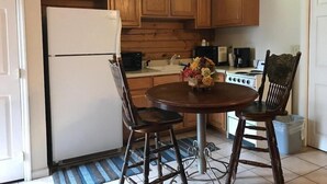 A kitchen with wooden cabinets, a refrigerator, a stove, and a dining table with chairs. - River Place Inn (Pigeon Forge)