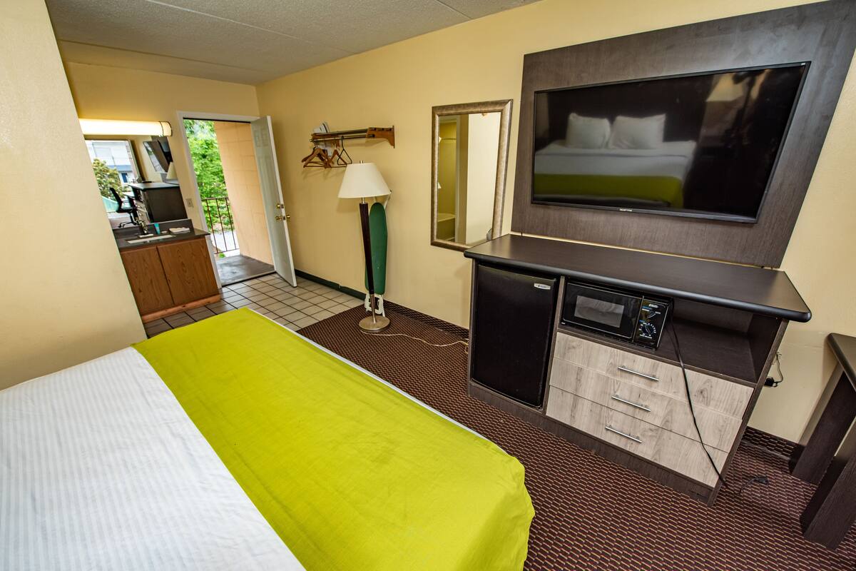 A hotel room with a bed, a TV, a desk, and a mirror.