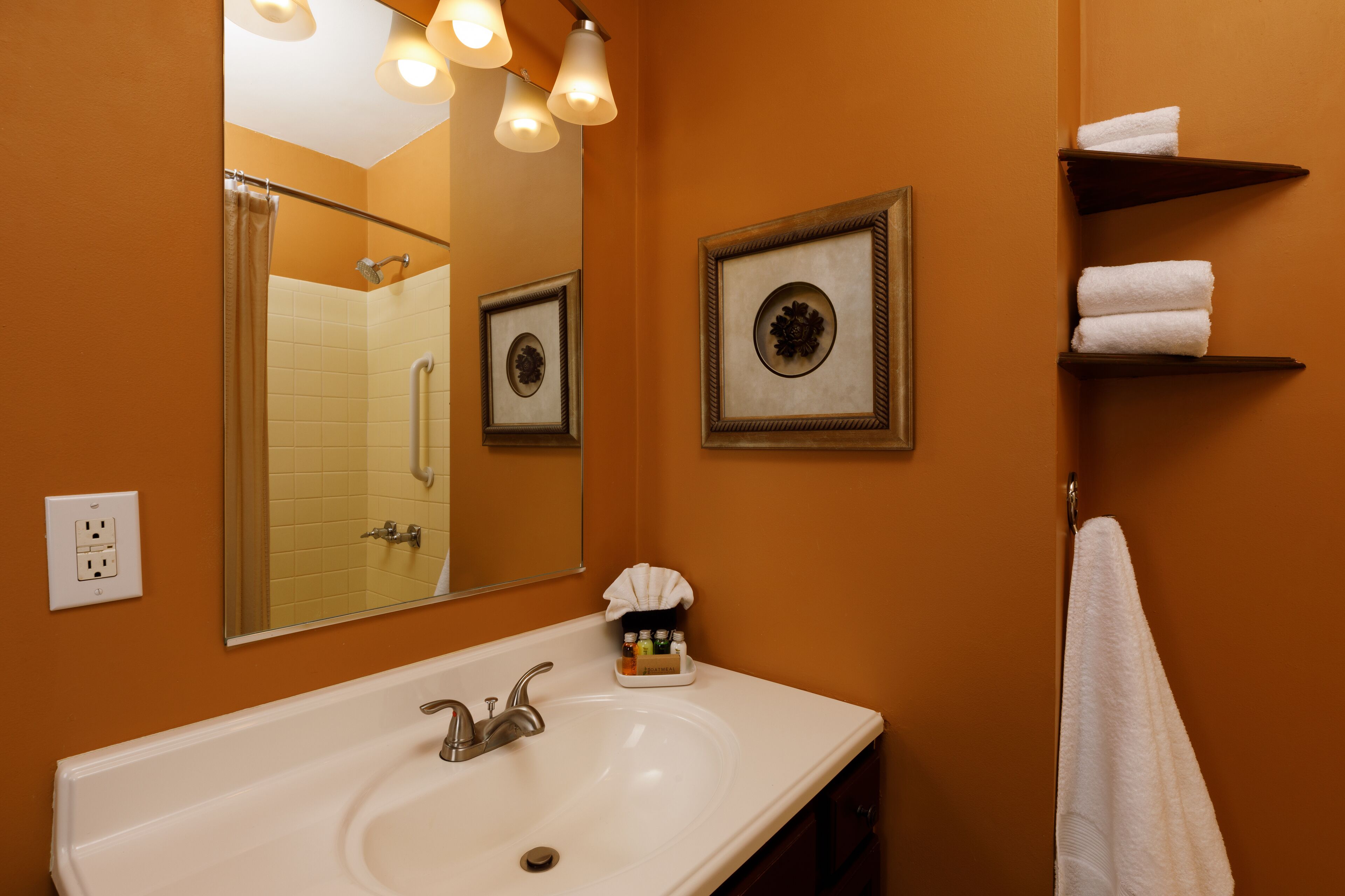 A bathroom with a white sink, a large mirror, and framed pictures on the wall.