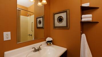 A bathroom with a white sink, a large mirror, and framed pictures on the wall.