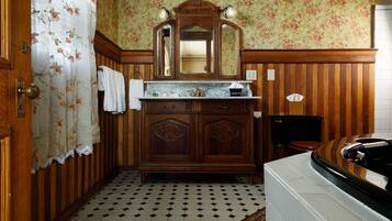 Un baño con un mueble de tocador de madera, un espejo y piso de baldosas.