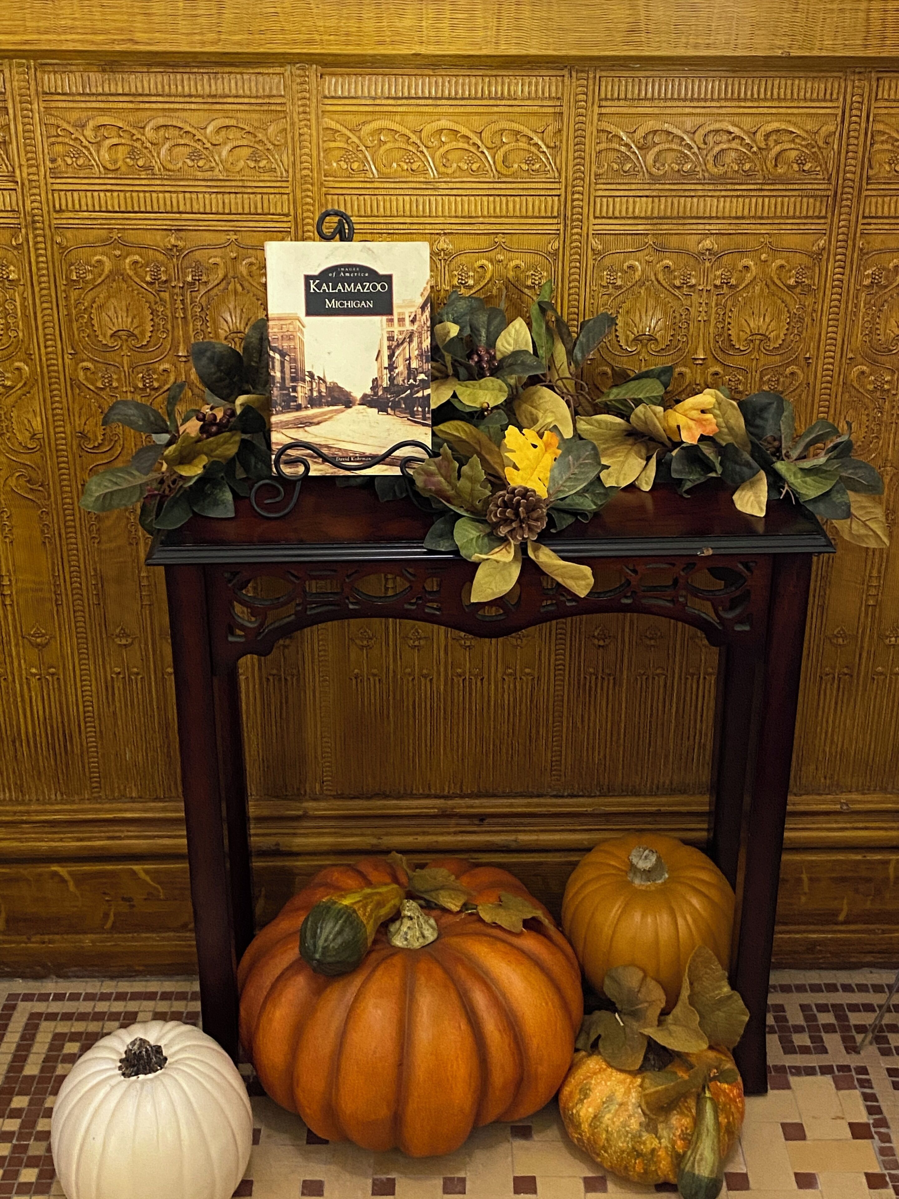 A table with a book titled 'Kalamazoo Michigan' and decorative foliage.