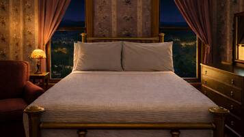 A bed with a headboard, a nightstand with a lamp, a chair, and a dresser.