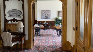 A dining area with a patterned carpet, wooden furniture, and a decorative archway. - The Kalamazoo House Downtown Hotel & Suites (Kalamazoo)