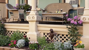 An outdoor seating area with wicker furniture and a decorative frog statue. - The Kalamazoo House Downtown Hotel & Suites (Kalamazoo)
