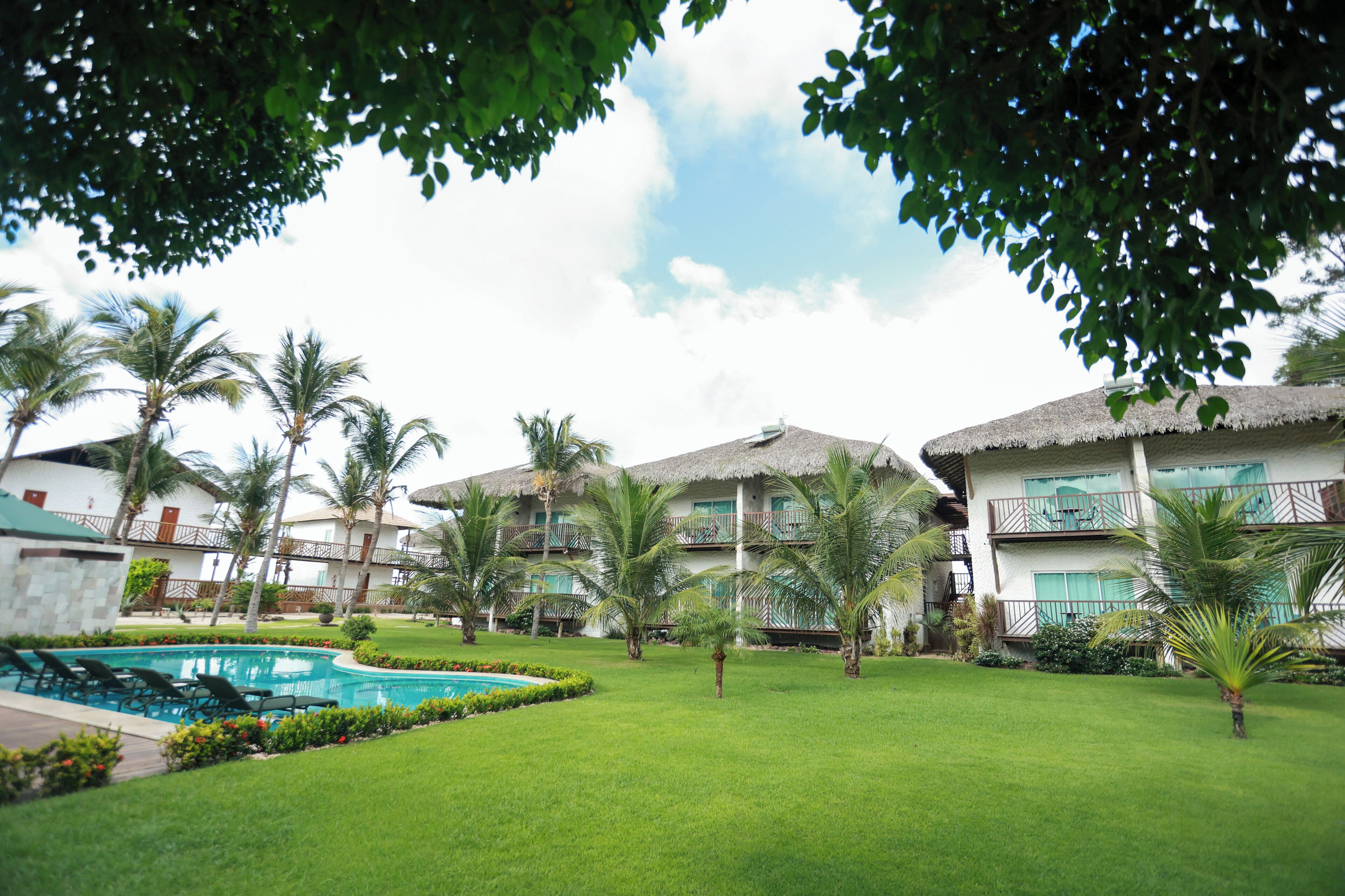 A resort with multiple two-story buildings, a swimming pool, and well-maintained lawns.