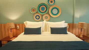 Una cama con una colcha blanco y verde oscuro, dos almohadas y un cabecero con un adorno circular en la pared.