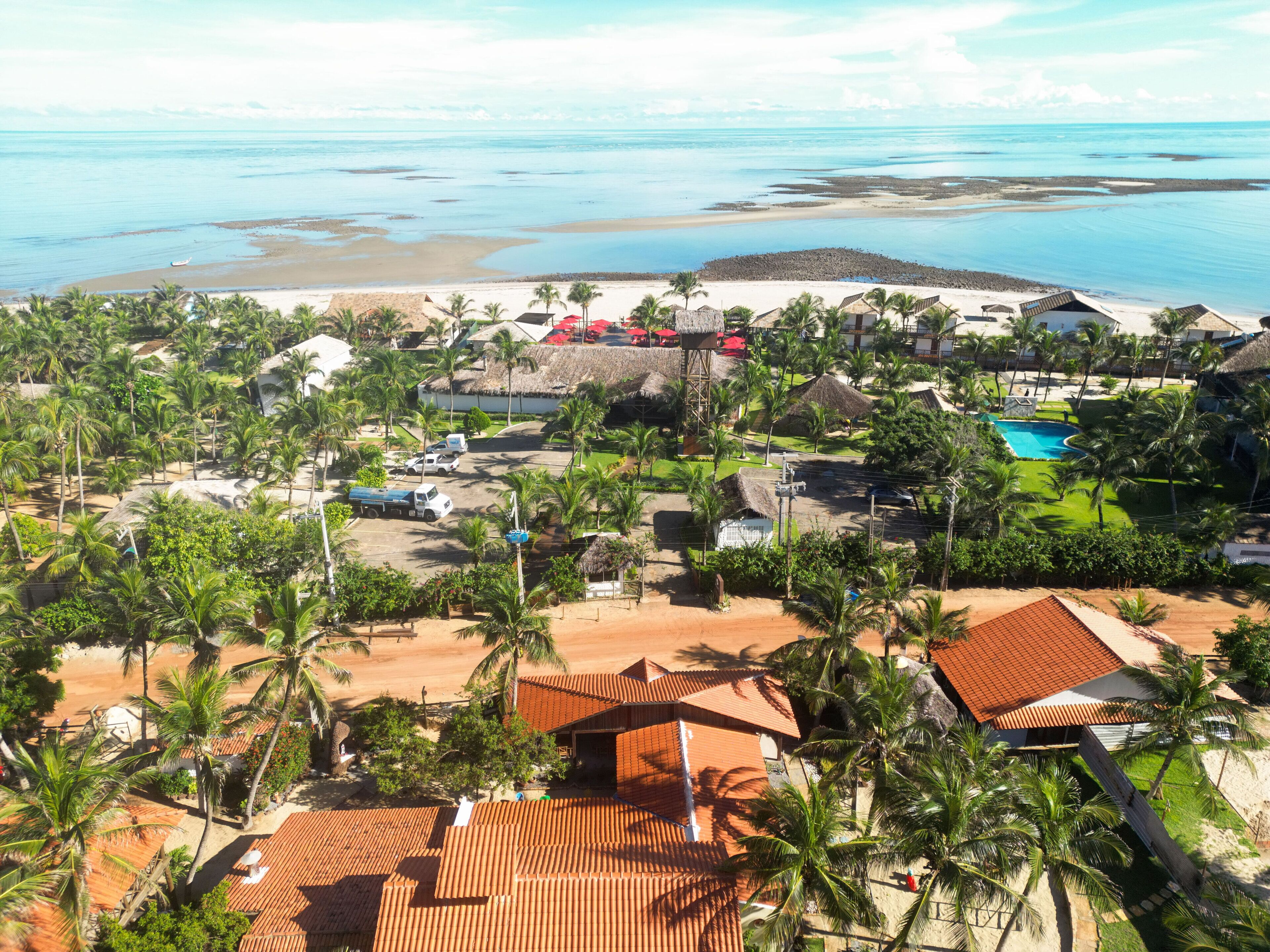 A resort with multiple buildings, a swimming pool, and a beach area.