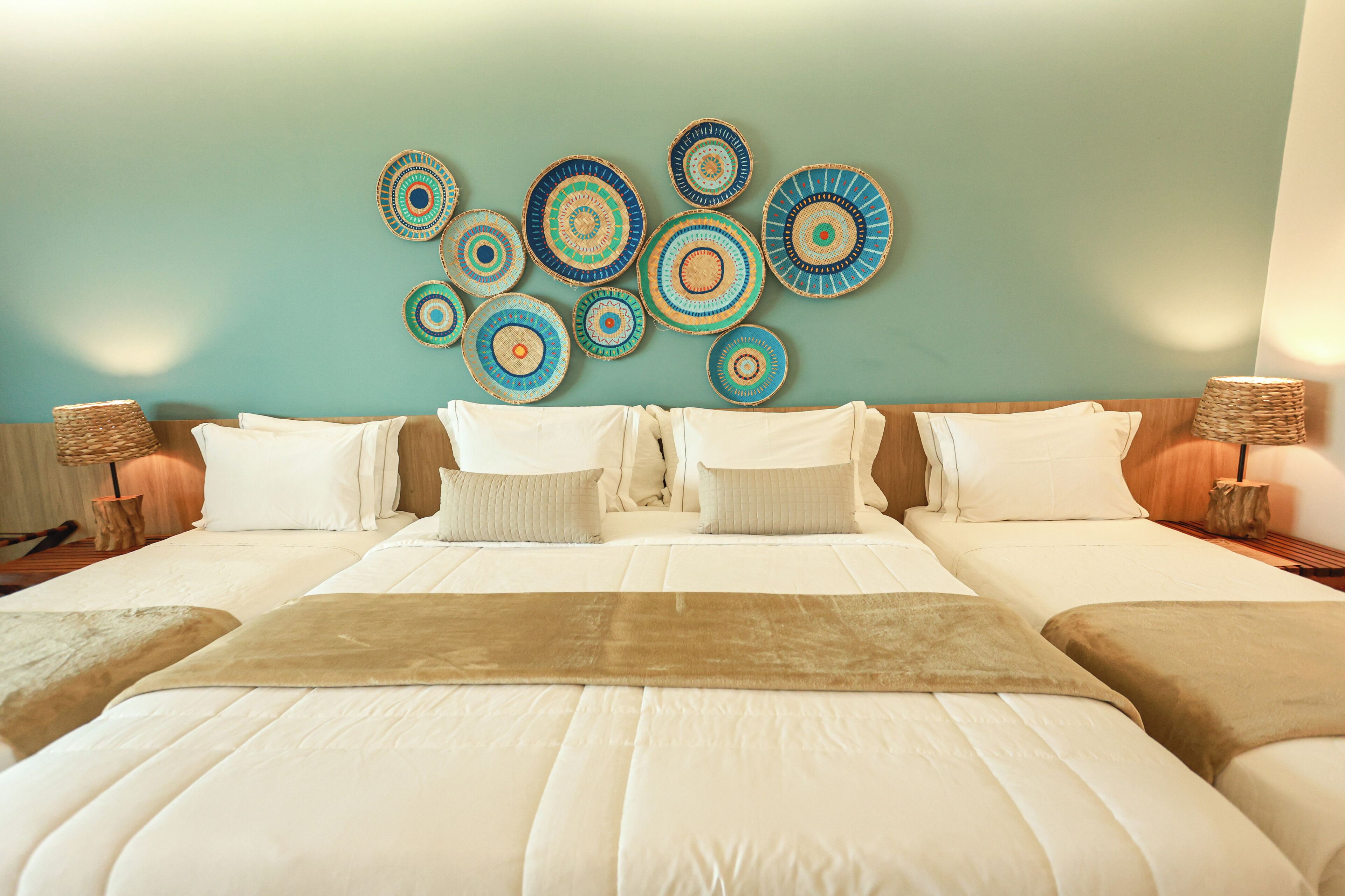 A hotel room with a large bed, two bedside tables, and a wall decorated with circular woven art pieces.