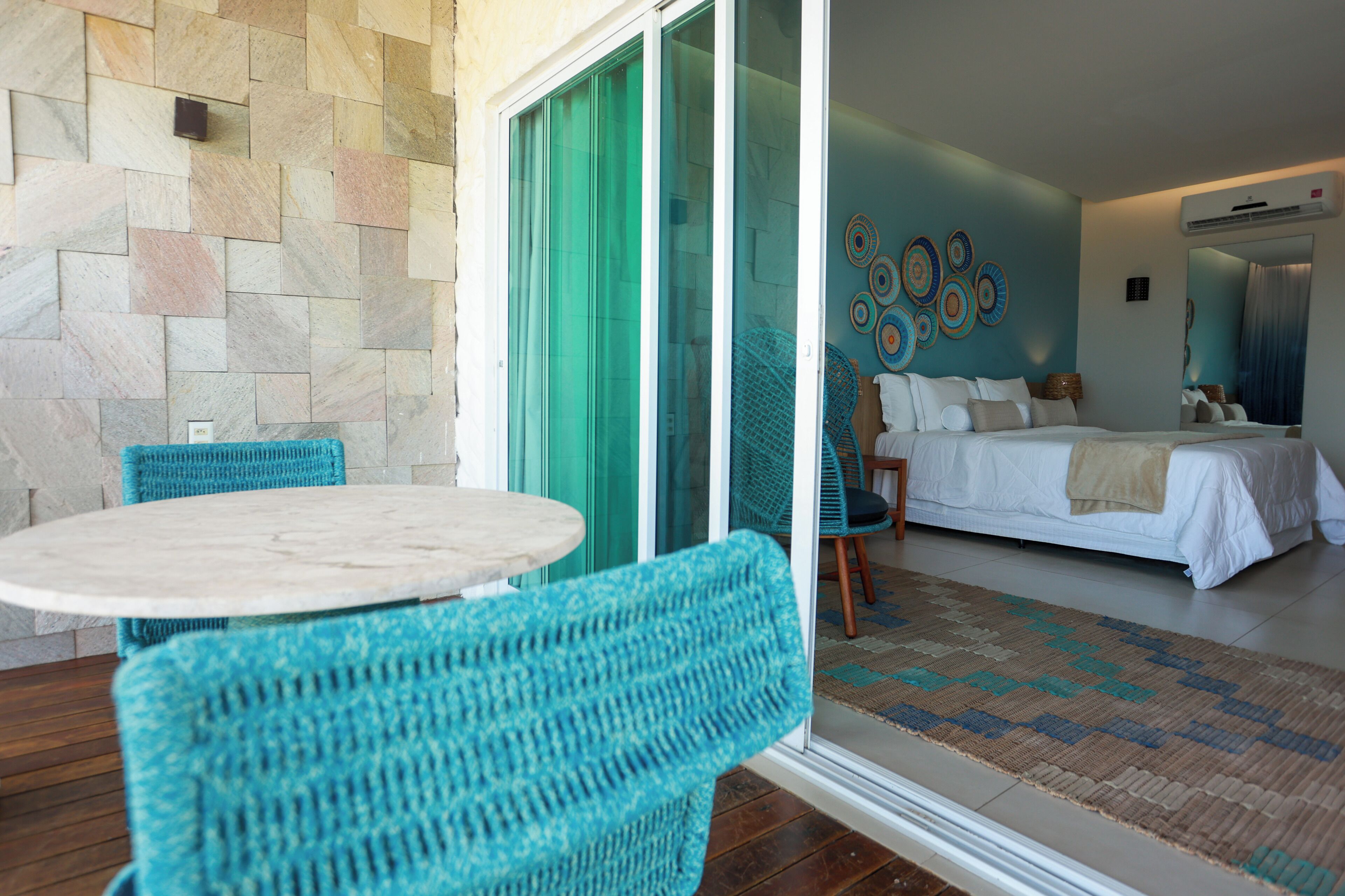 A hotel room with a bed, a bathroom, and a balcony with a table and chairs.