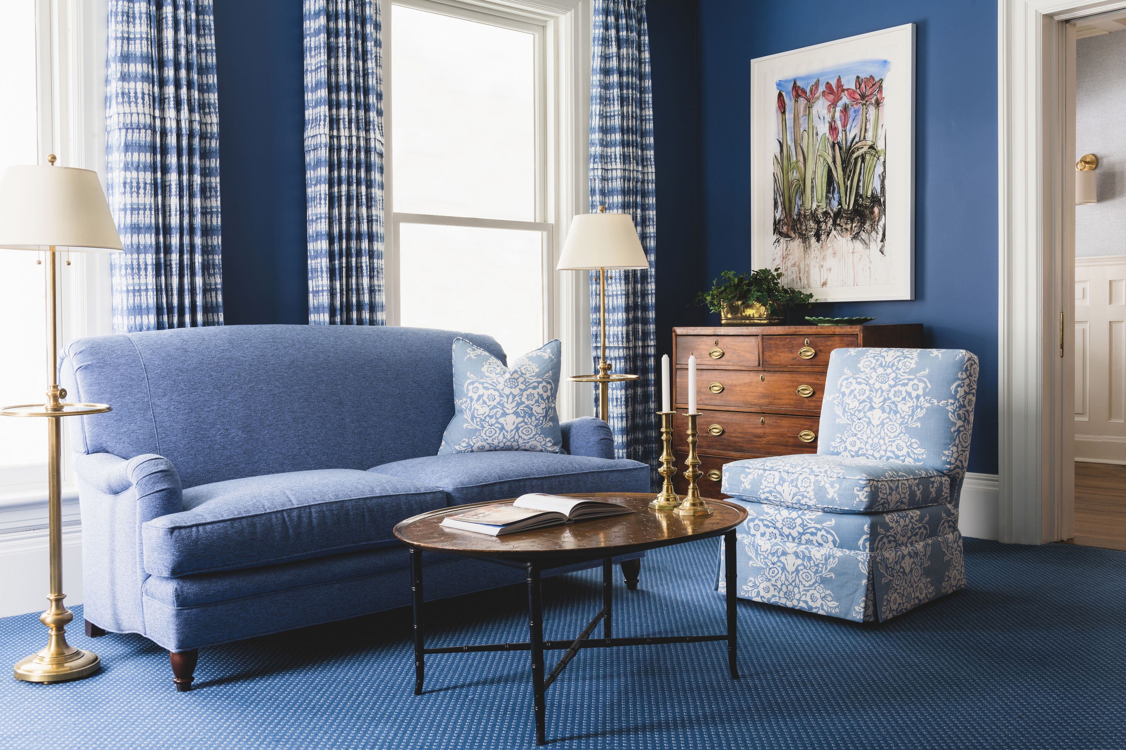 A room with a blue sofa, a matching armchair, a wooden coffee table, and a dresser with drawers.