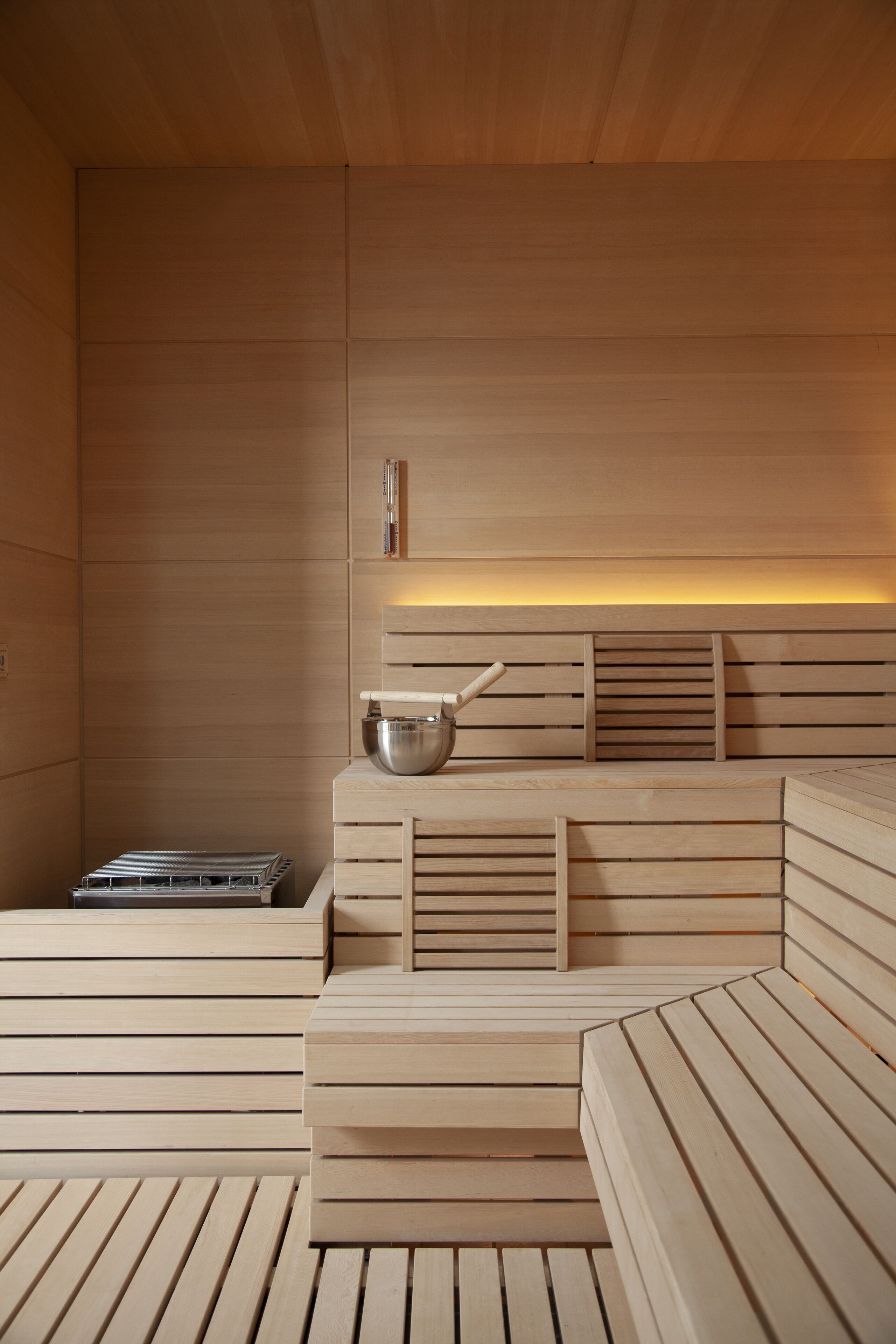 Un sauna con bancos de madera y un recipiente metálico.