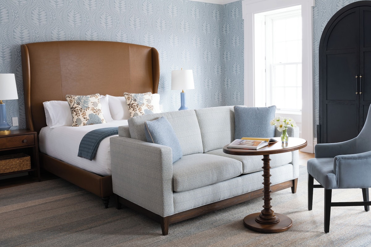 A bedroom with a bed, a sofa, a chair, and a table.