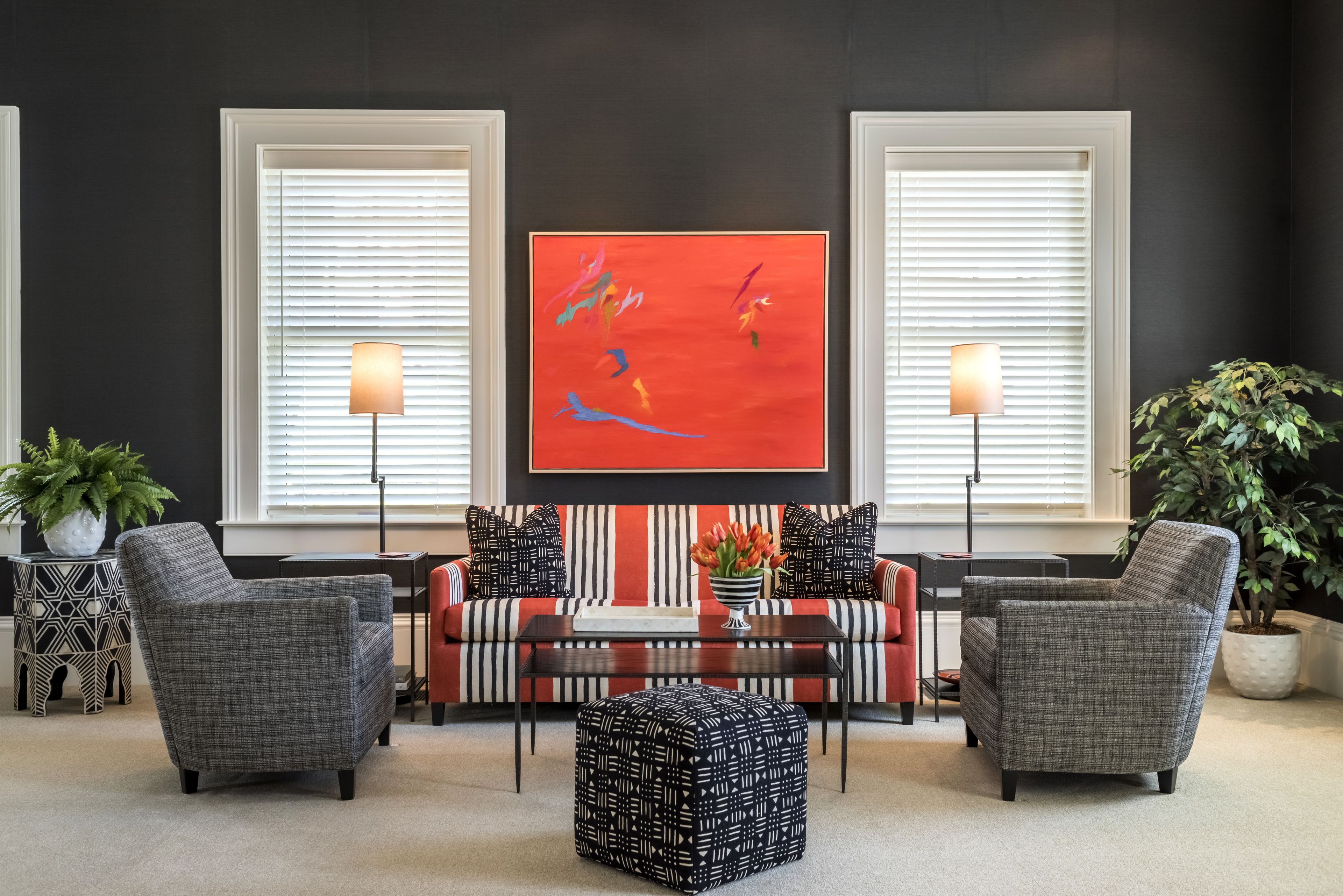 A living room with a sofa, two armchairs, a coffee table, and a red abstract painting on the wall.