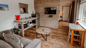 Una sala de estar moderna con un sofá gris, una mesa de centro de madera y un televisor montado en una pared de madera.