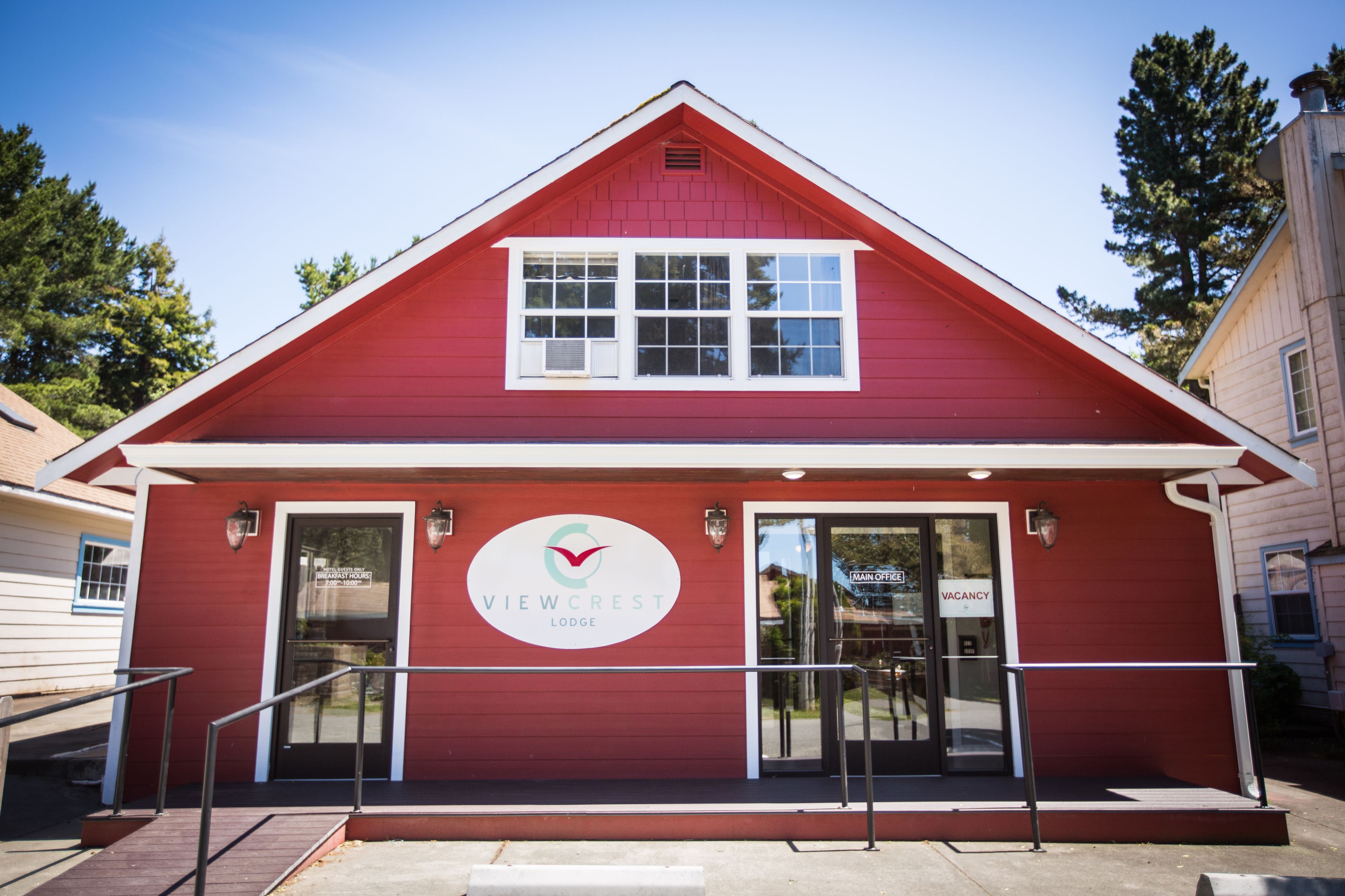 Un bâtiment rouge avec une enseigne indiquant « VIEWCREST LODGE » et un panneau « CHAMBRES LIBRES » sur la porte.