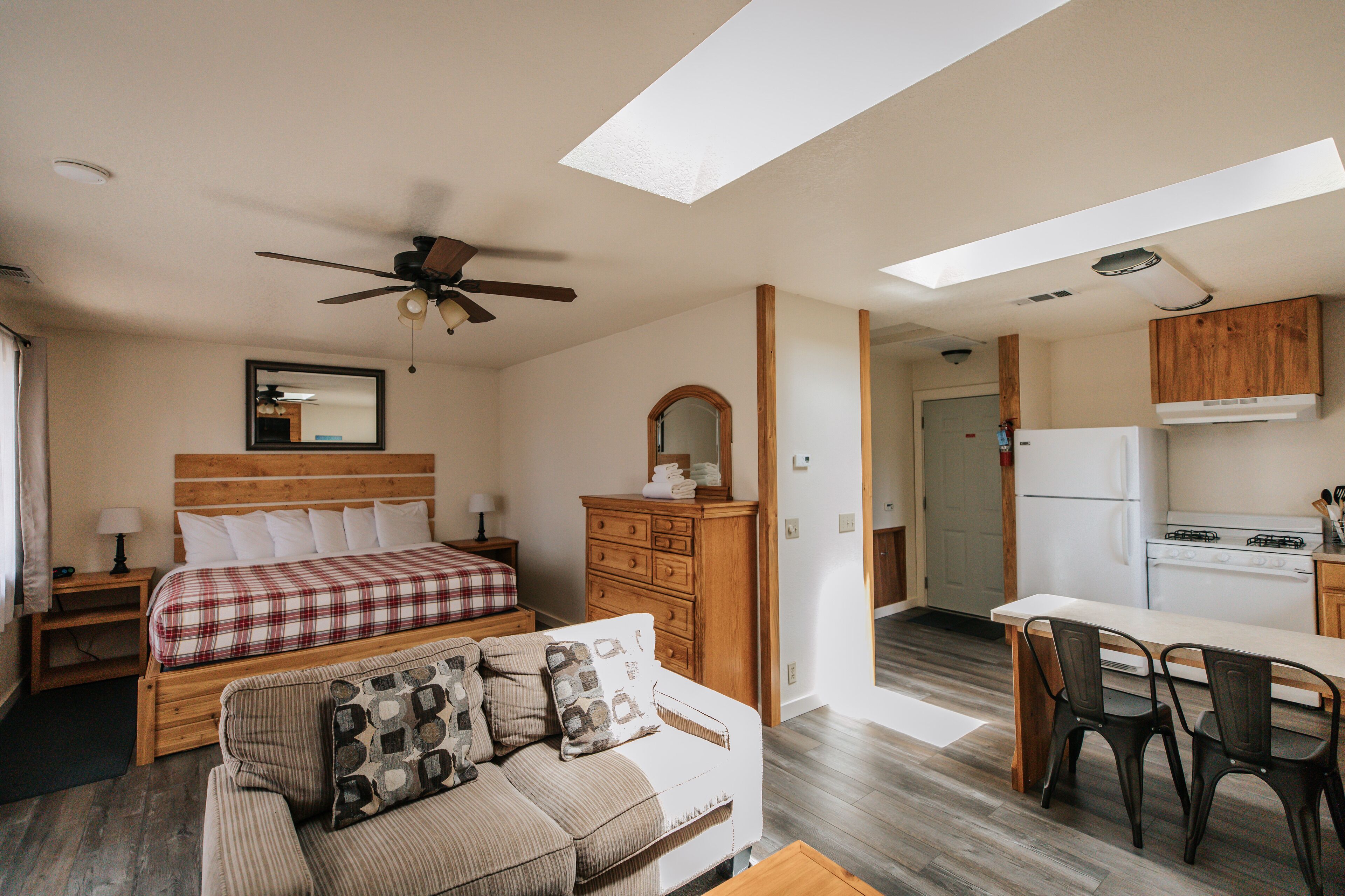 A bedroom with a bed, a wooden dresser, a mirror, and a ceiling fan.