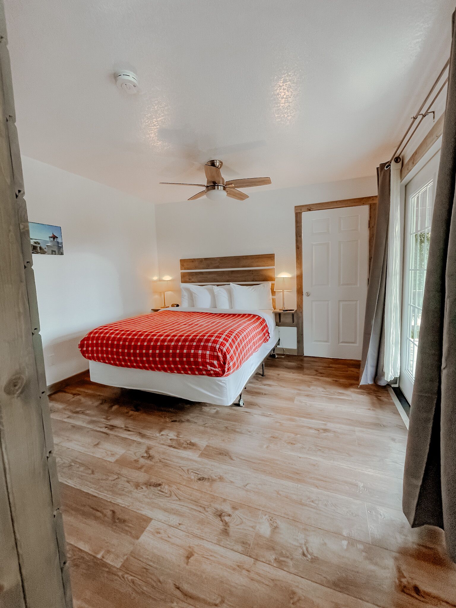 Une chambre à coucher avec un lit, un ventilateur de plafond, une table de chevet et une porte.