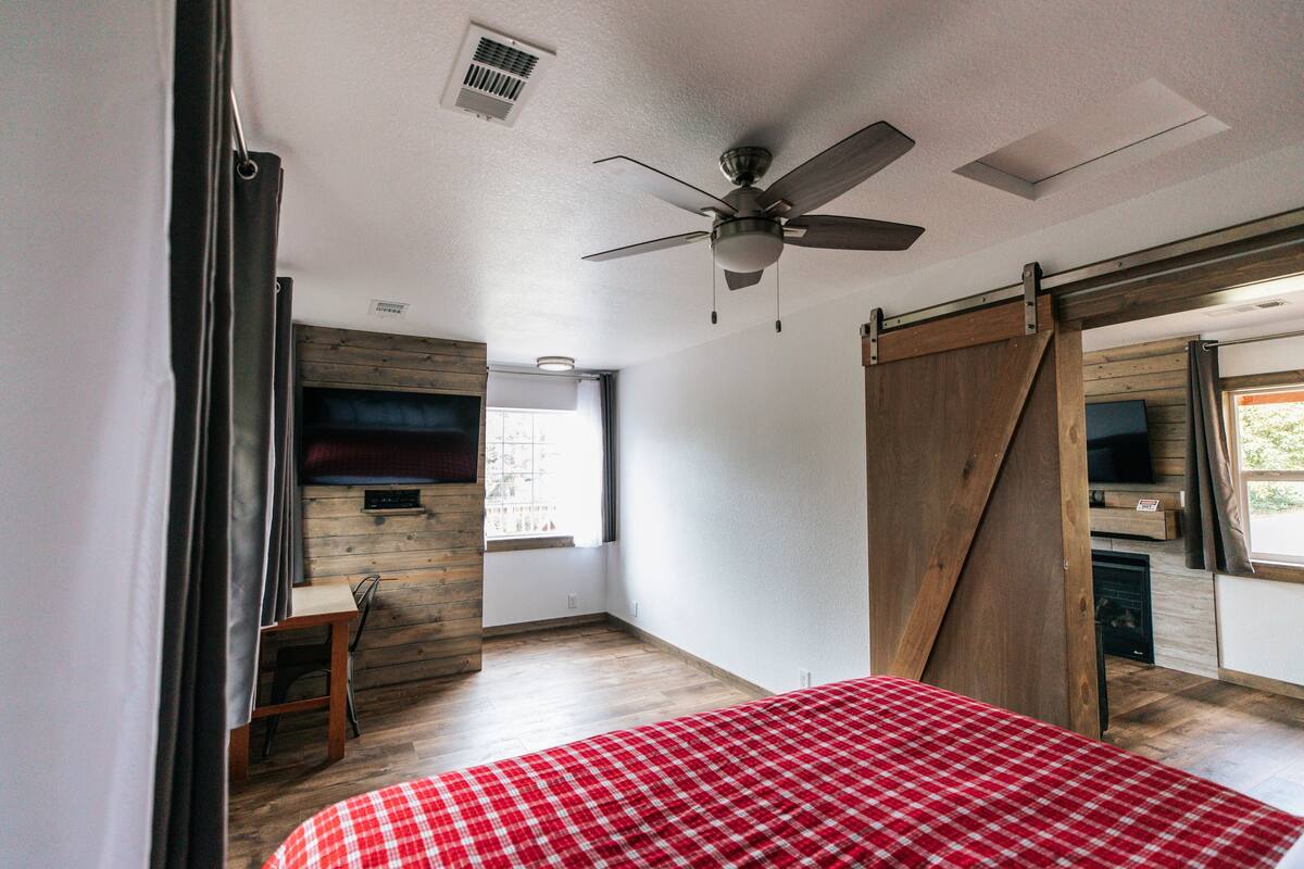 A bedroom with a bed, a ceiling fan, a TV, and a sliding barn door.