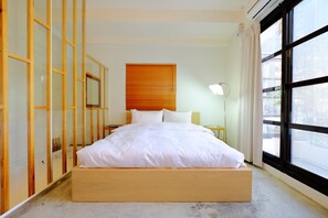 A bedroom with a wooden bed frame, a large window with curtains, and a bedside lamp. - Two Meters Lane Two Hall (Tainan)
