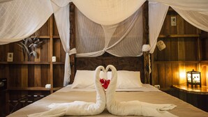 A bed with a canopy and two towels shaped like swans with a red flower in the center. - Tierra de Sueños Lodge & Wellness Center (Cahuita)