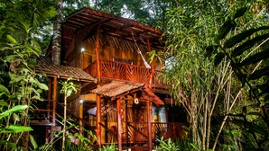 A wooden house with a balcony, surrounded by dense tropical vegetation. - Tierra de Sueños Lodge & Wellness Center (Cahuita)