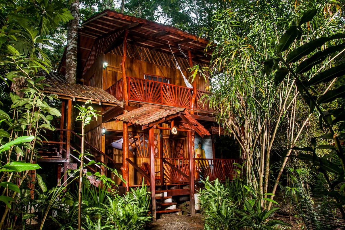 Une maison en bois dot ée d’un balcon, entourée d’une végétation tropicale luxuriante.