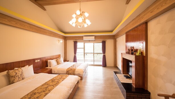A hotel room with two beds, a chandelier, a fireplace, and a large window with curtains. - Coconut Grove House B and B (Hengchun)