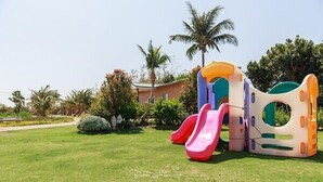 A playground with slides and a house in the background. - Coconut Grove House B and B (Hengchun)