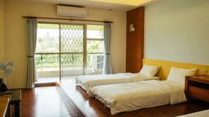 A hotel room with two beds, a wooden headboard, a small bedside table, and a window with a view of greenery. - Coconut Grove House B and B (Hengchun)