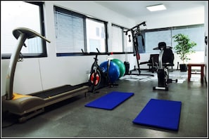 A gym with exercise equipment, blue mats, and a treadmill. - Hotel Florida (Villa Carlos Paz)