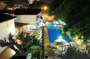A rooftop pool area with lounge chairs and umbrellas, surrounded by trees and buildings. - Hotel Florida (Villa Carlos Paz)